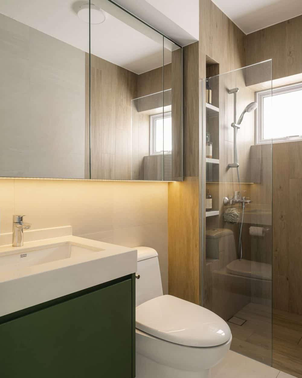 Bathroom with forest green vanity, white undermount basin, mirrored cabinet with LED strip, wood-look tiles and glass shower screen